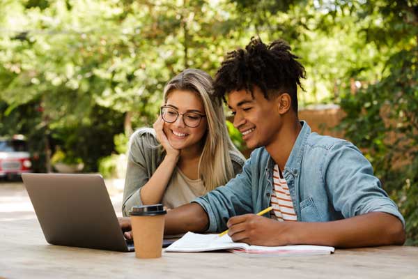 two people in front of laptop computer with coffee and notebook